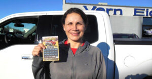 Woman holding scratch ticket in front of truck